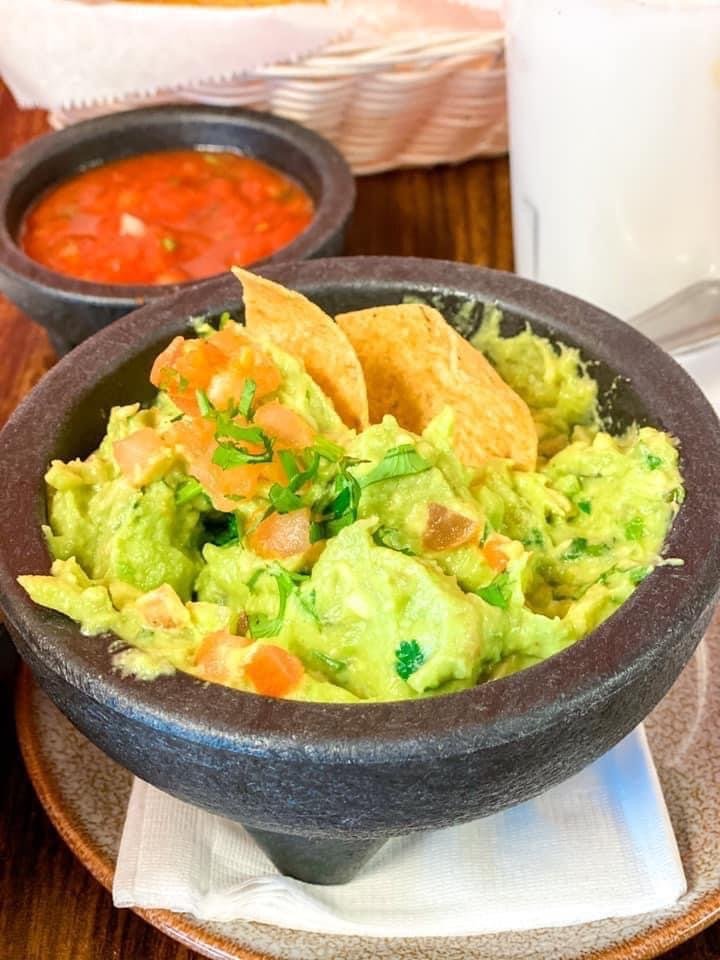 Fresh guacamole served in a traditional molcajete with chips and salsa